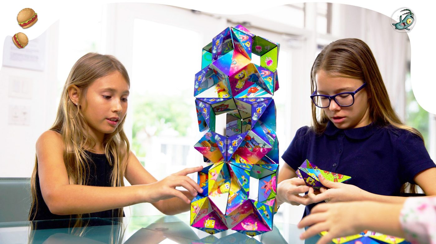 Kids building a tall tower from several Shashibo cubes